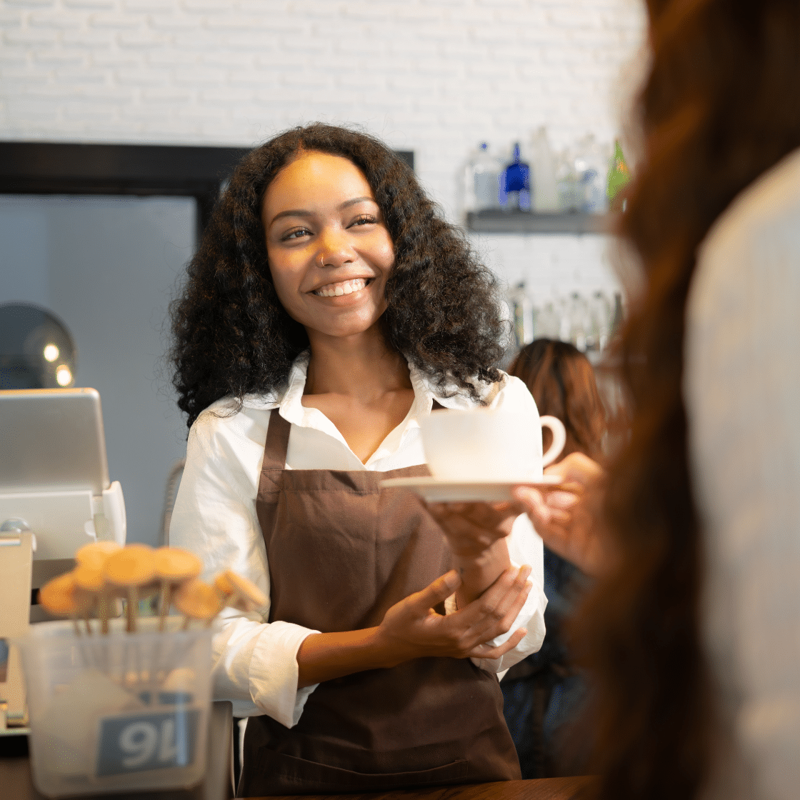 Smiling barista, café, handing customer coffee