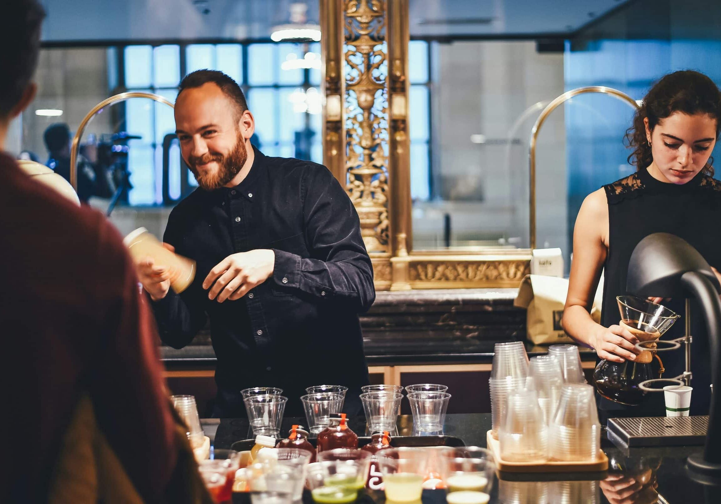 Baristas behind bar making beverages, beverage shaker, coffee and tea and more